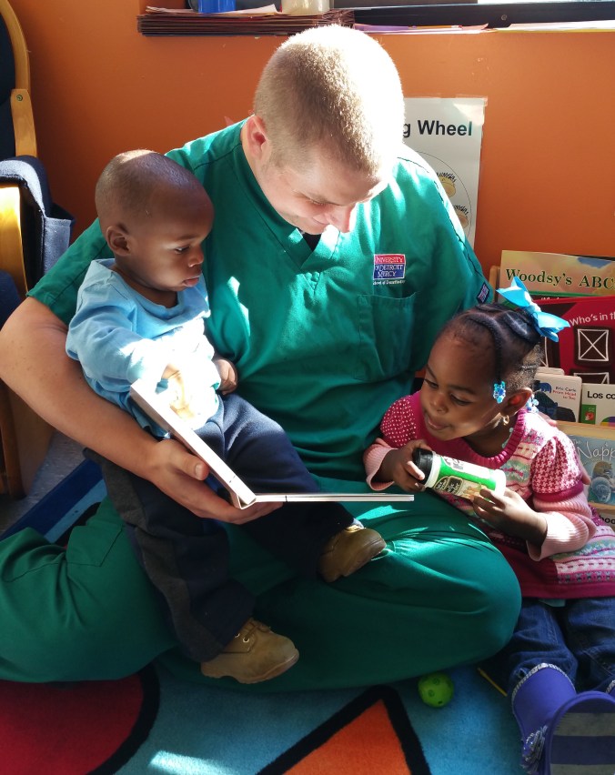 UDM senior dental student David Posthumus reads with Julius and Ahlinius Grant.