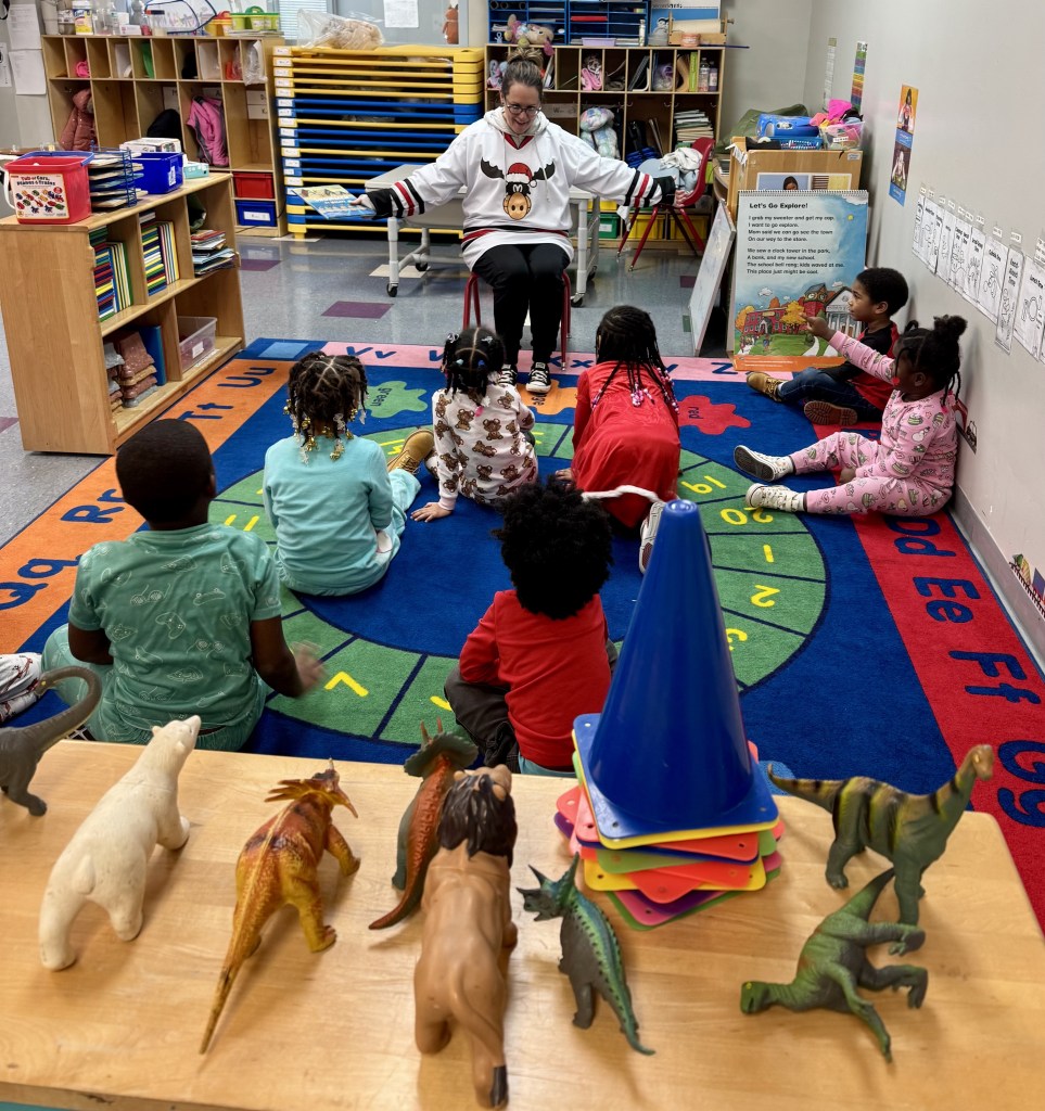 Melissa Converse sits in a chair preparing to read to kids in one of the Harper/Gratiot classrooms